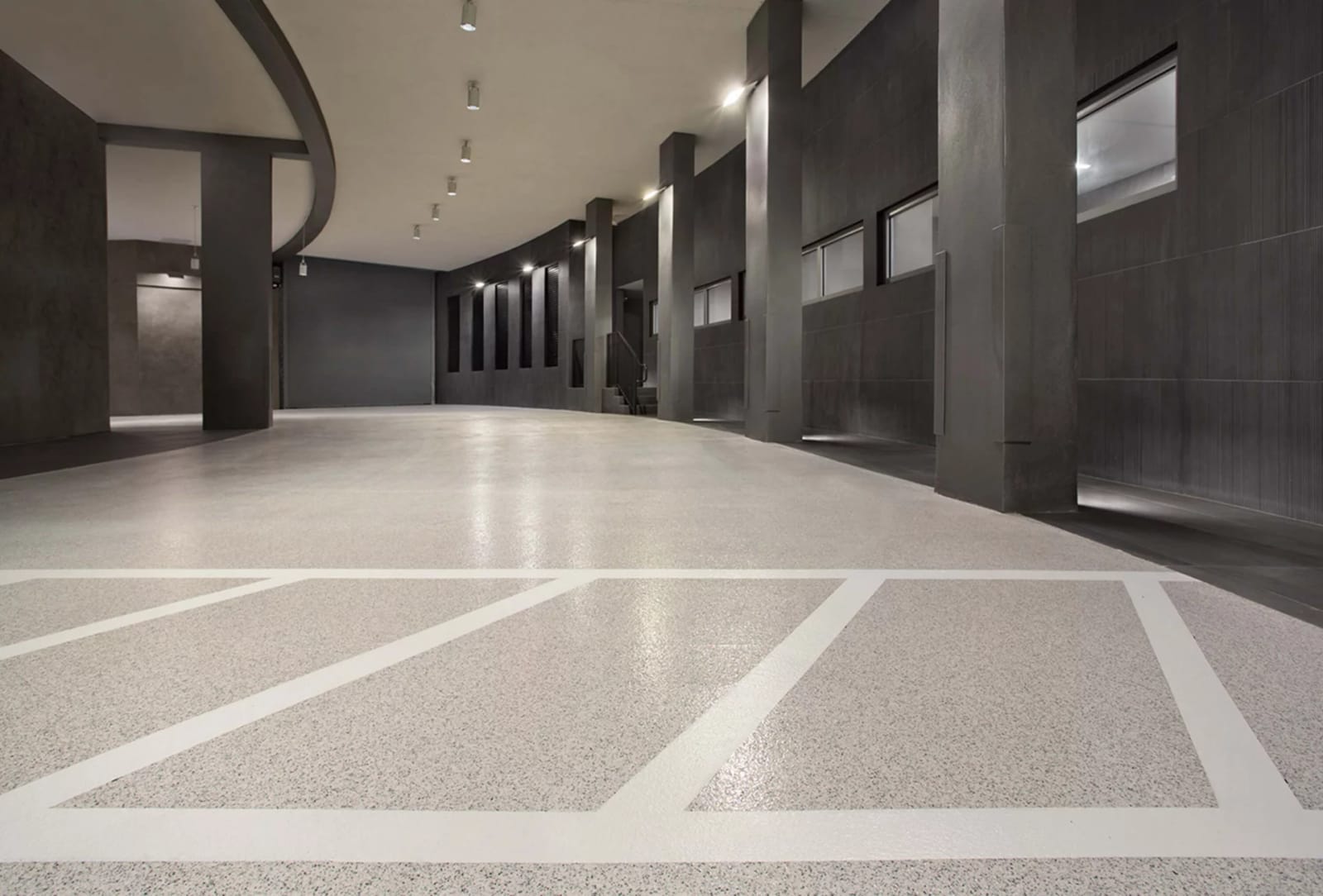 Overdekte inrijzone van een autobedrijf met een lichte gietvloer met kleurchips en witte belijning