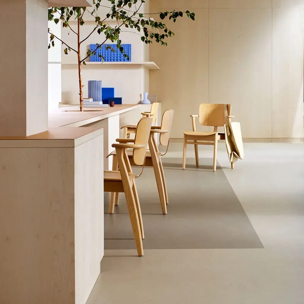 Pantry met houten stoelen aan een lange werkbank op een lichtgrijze marmoleumvloer