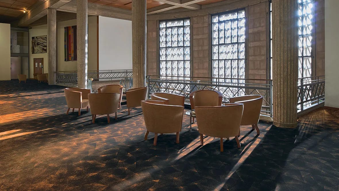 Foyer met leren fauteuils bij een balustrade op een donkere Flotex-vloer met patroon