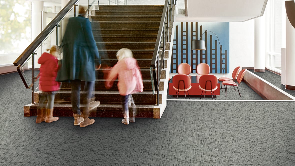 Trappenhal van een school met een ouder en twee kinderen op een antraciet Flotex-vloer