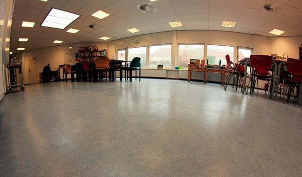 Lichte ruimte in Basisschool Smidse met tafels bij de ramen en een grijze marmoleumvloer