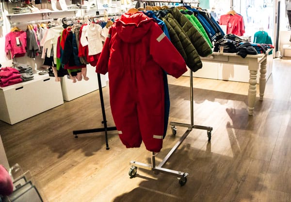 Babykledingwinkel Ikke&Mama met een rood skipak aan een kledingrek op een houtlook PVC-vloer