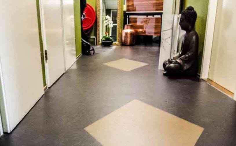 Gang in Inloophuis Wij Allemaal met donker marmoleum, lichte ruitvormige inleg en een Boeddhabeeld