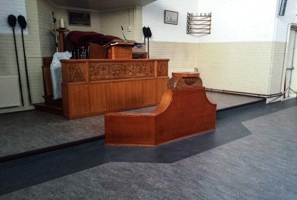 Houten kansel en kerkmeubilair in een kerk in Purmerend op grijs marmoleum in twee tinten