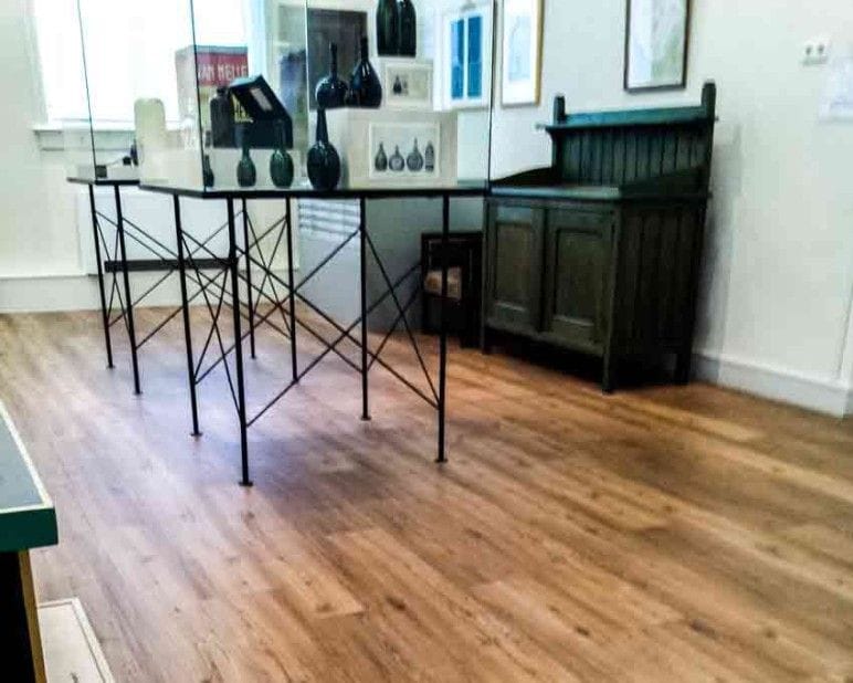Expositiezaal in het Purmerends Museum met een vitrinetafel en een antieke kast op houtlook PVC