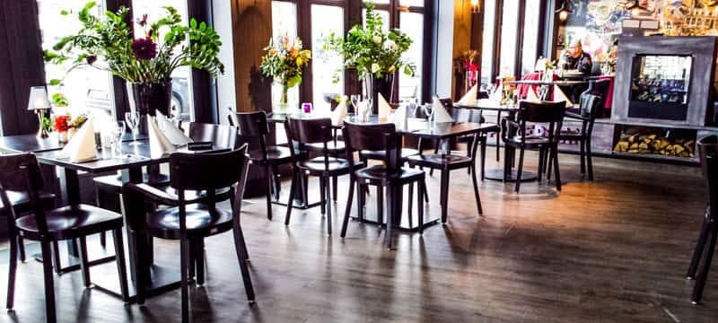 Eetzaal van Restaurant Spijkerman met donkere stoelen en tafels op een houtlook PVC-vloer