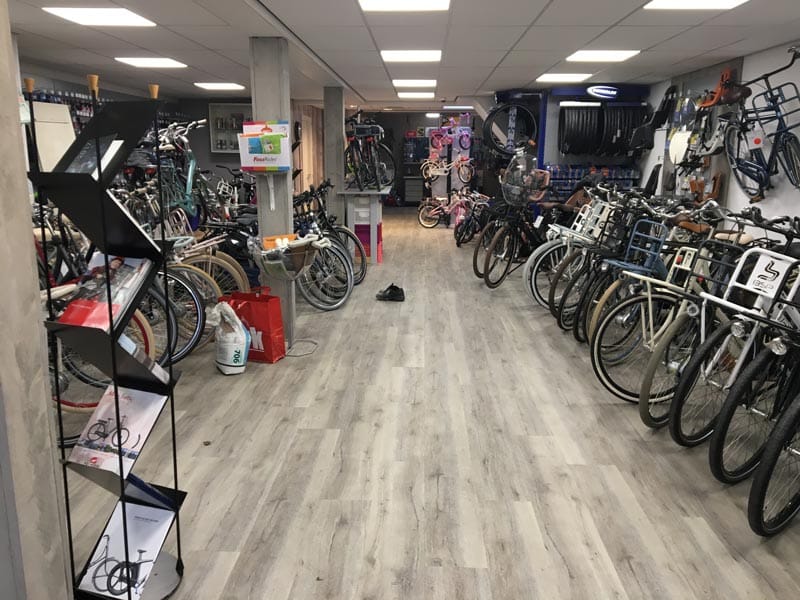Fietsenwinkel Rijwielhandel Purmerend met rijen fietsen op een grijze houtlook PVC-vloer