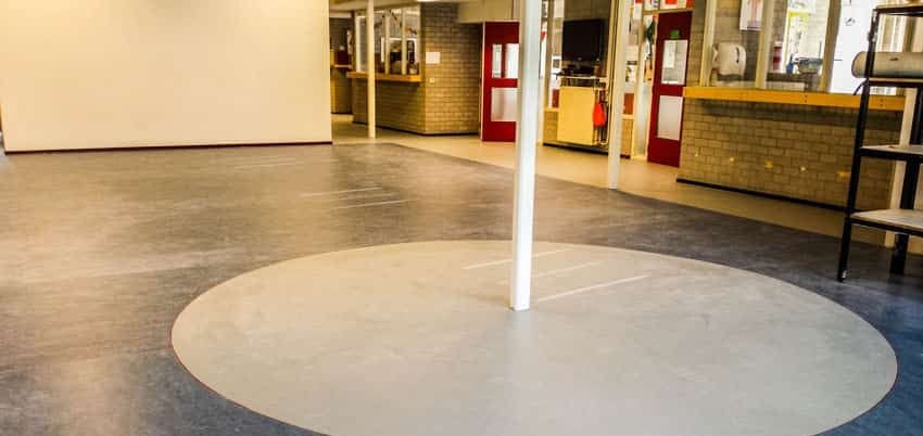Aula van basisschool De Vlieger met blauwgrijs marmoleum en een lichte cirkel rond een kolom