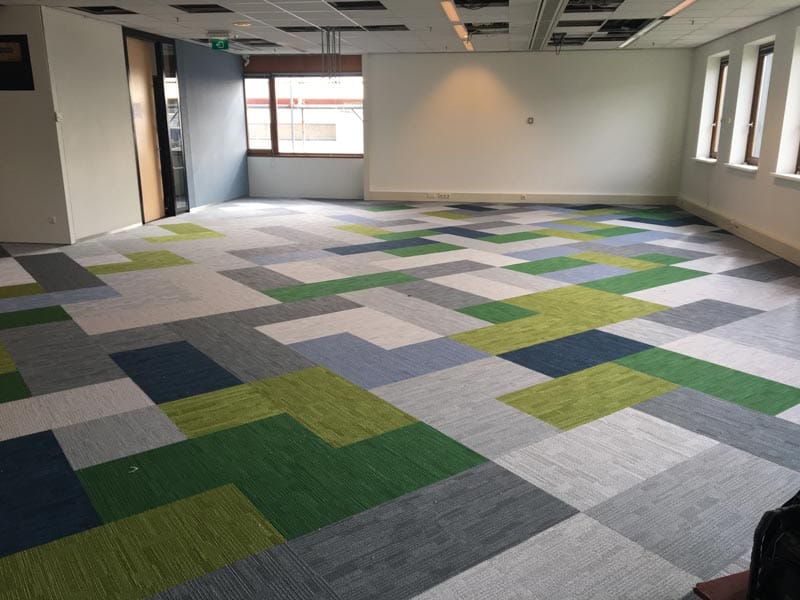 Lege kantoorverdieping met tapijttegels in een patroon van groen, blauw en grijs