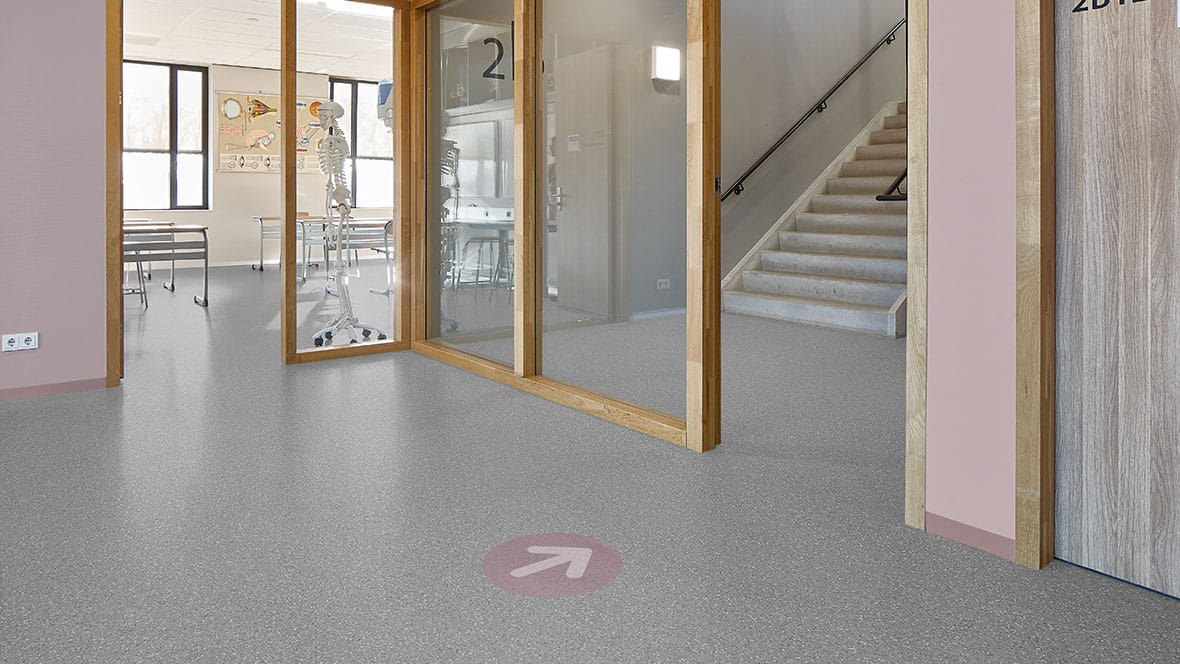 Grijze PVC-vloer in een schoolgang met trap