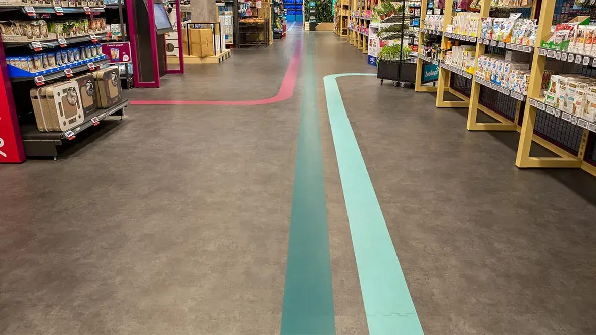 Winkelgangpad met een grijze vloer en gekleurde looplijnen tussen de schappen