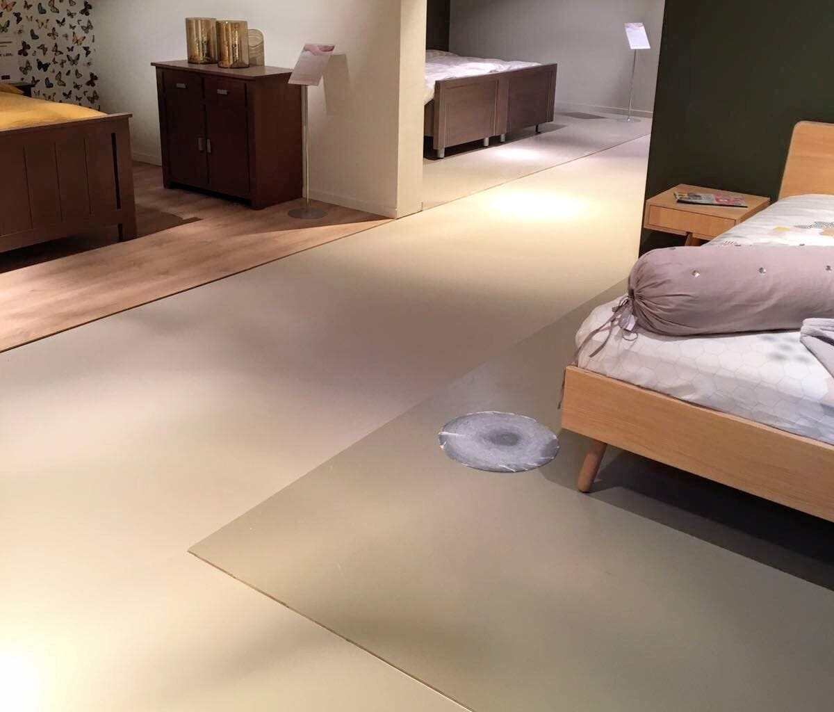 Beddenshowroom met een lichte naadloze gietvloer tussen de opstellingen
