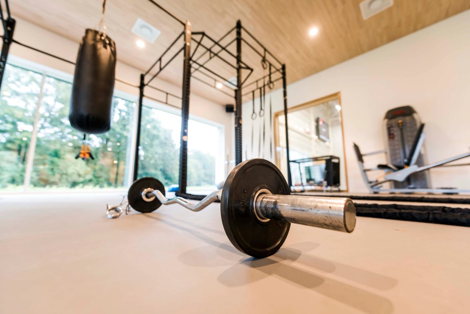 Lichte fitnessruimte met halterstang, bokszak en rek op een naadloze grijze vloer