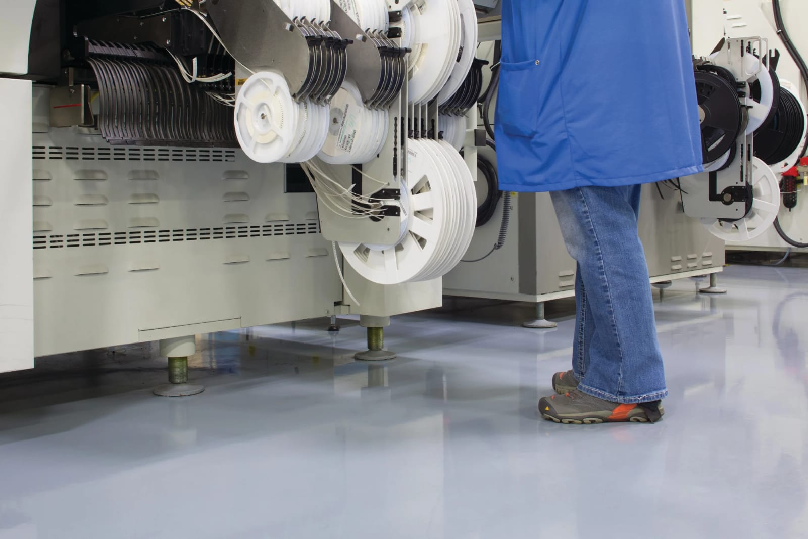 Medewerker bij een productiemachine op een grijze naadloze gietvloer