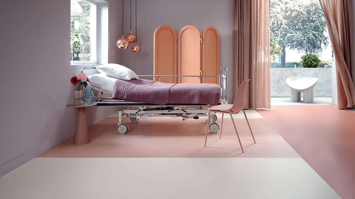 Patiëntenkamer met ziekenhuisbed op een lichte vloer met zachtroze vlakken